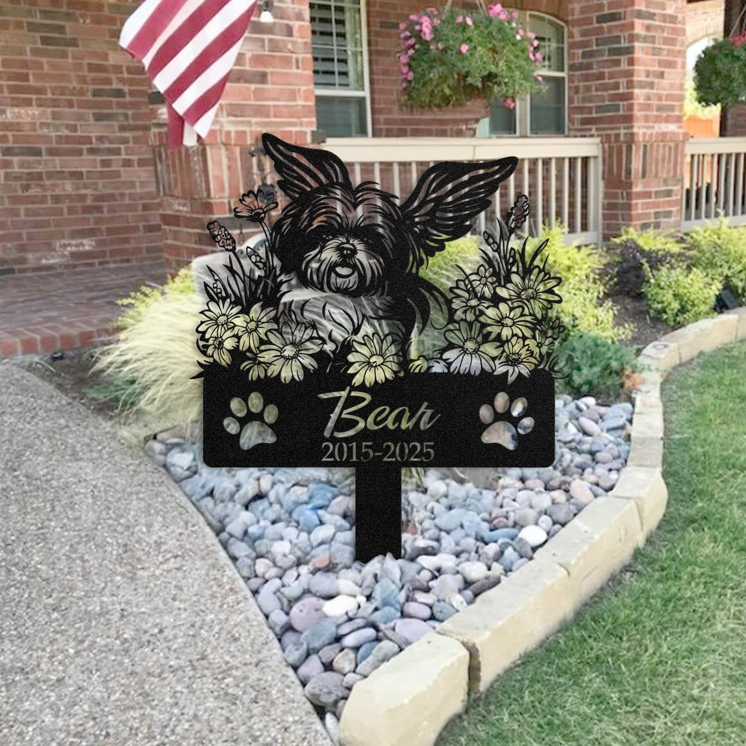 Shih Tzu pet grave marker staged near a home entryway, showing the finished angel wings and daisy floral design and name plate outdoors.