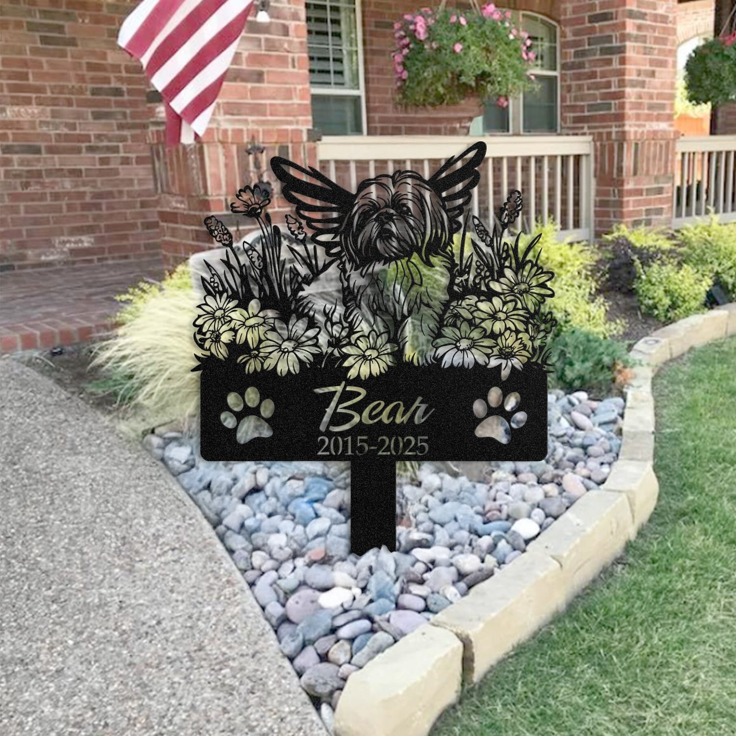 Shih Tzu pet grave marker staged near a home entryway, showing the finished angel wings and daisy floral design and name plate outdoors.