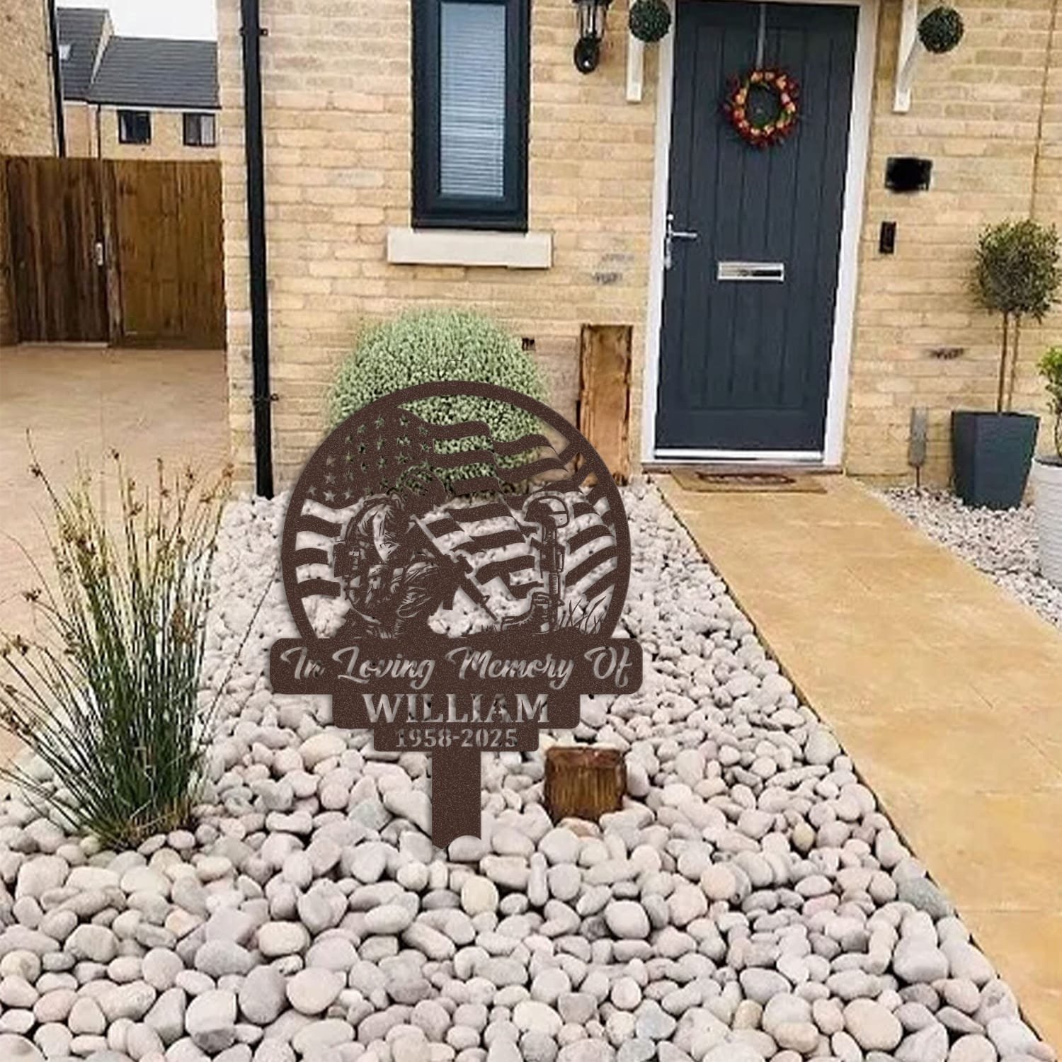 Soldier human grave marker displayed among garden plants and stone edging, showing the design as an outdoor memorial accent.