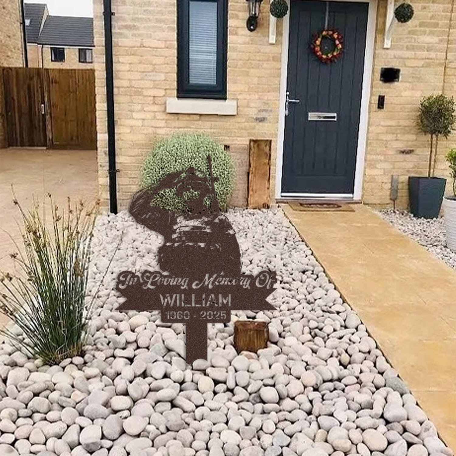 Soldier human grave marker displayed among garden plants and stone edging, showing the design as an outdoor memorial accent.