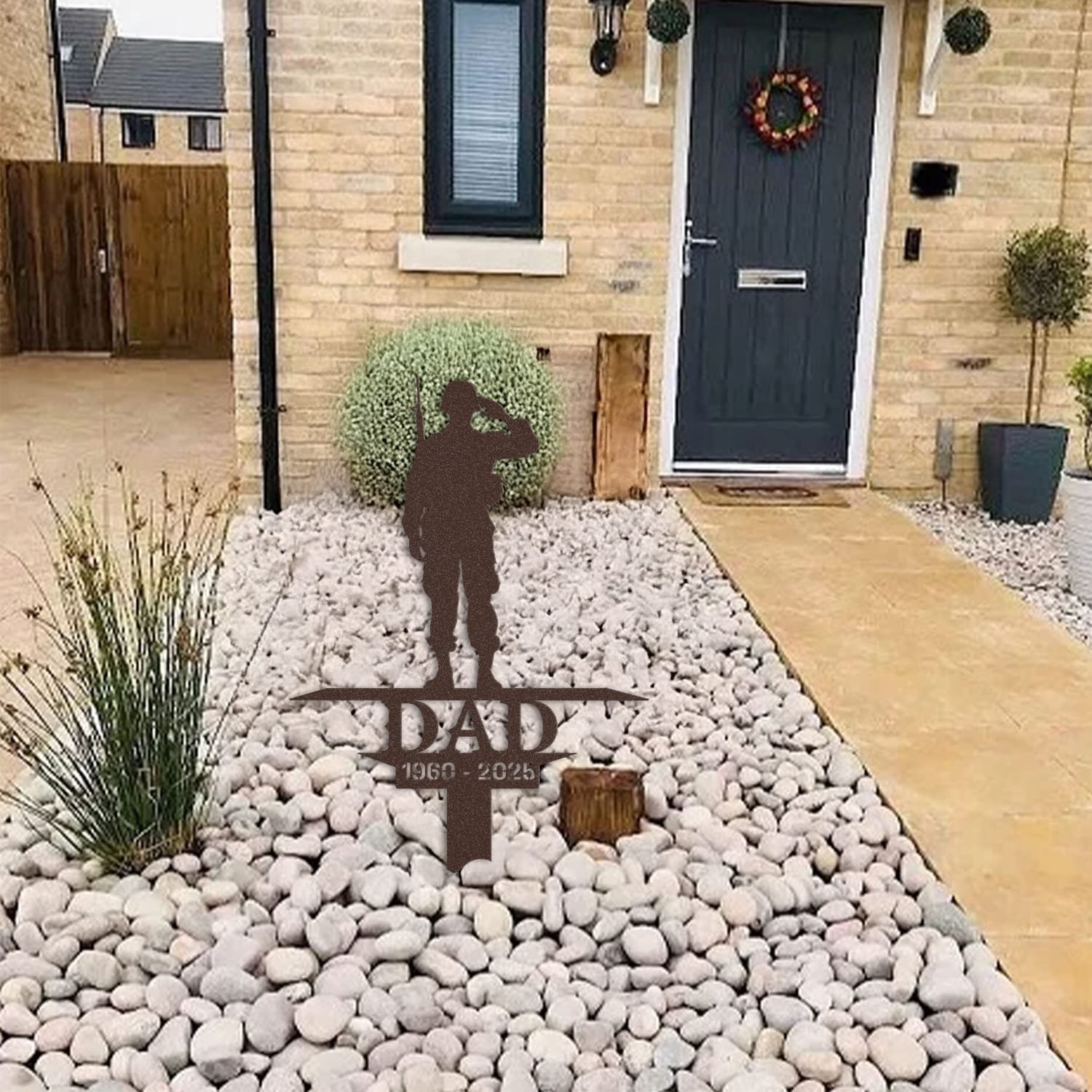 Soldier human grave marker displayed among garden plants and stone edging, showing the design as an outdoor memorial accent.