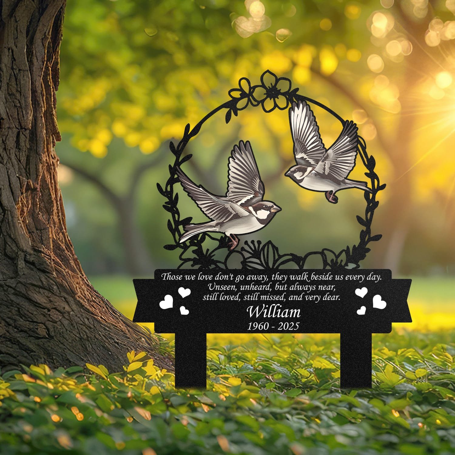 Sparrow human grave marker displayed outdoors in a garden setting, showing the personalized floral wreath bird-pair design in place on the stake.