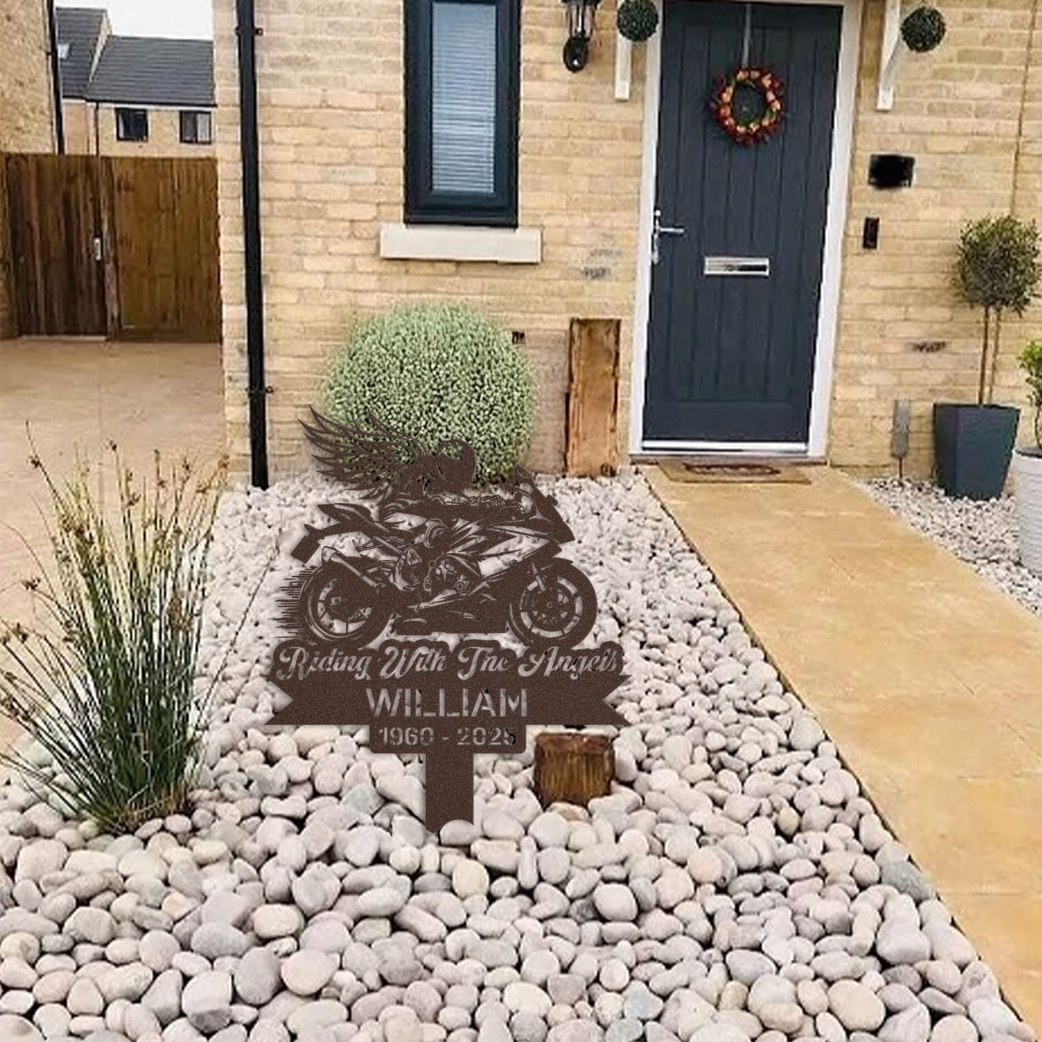 Sport Motorcycle human grave marker displayed among garden plants and stone edging, showing the sport motorcycle winged rider design as an outdoor memorial accent.