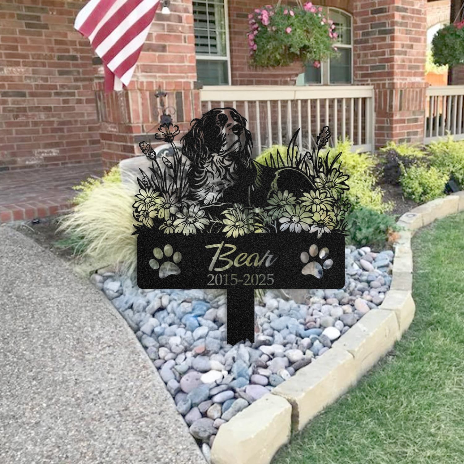 Springer Spaniel pet grave marker staged near a home entryway, showing the finished sleeping-pose daisy floral design and name plate outdoors.