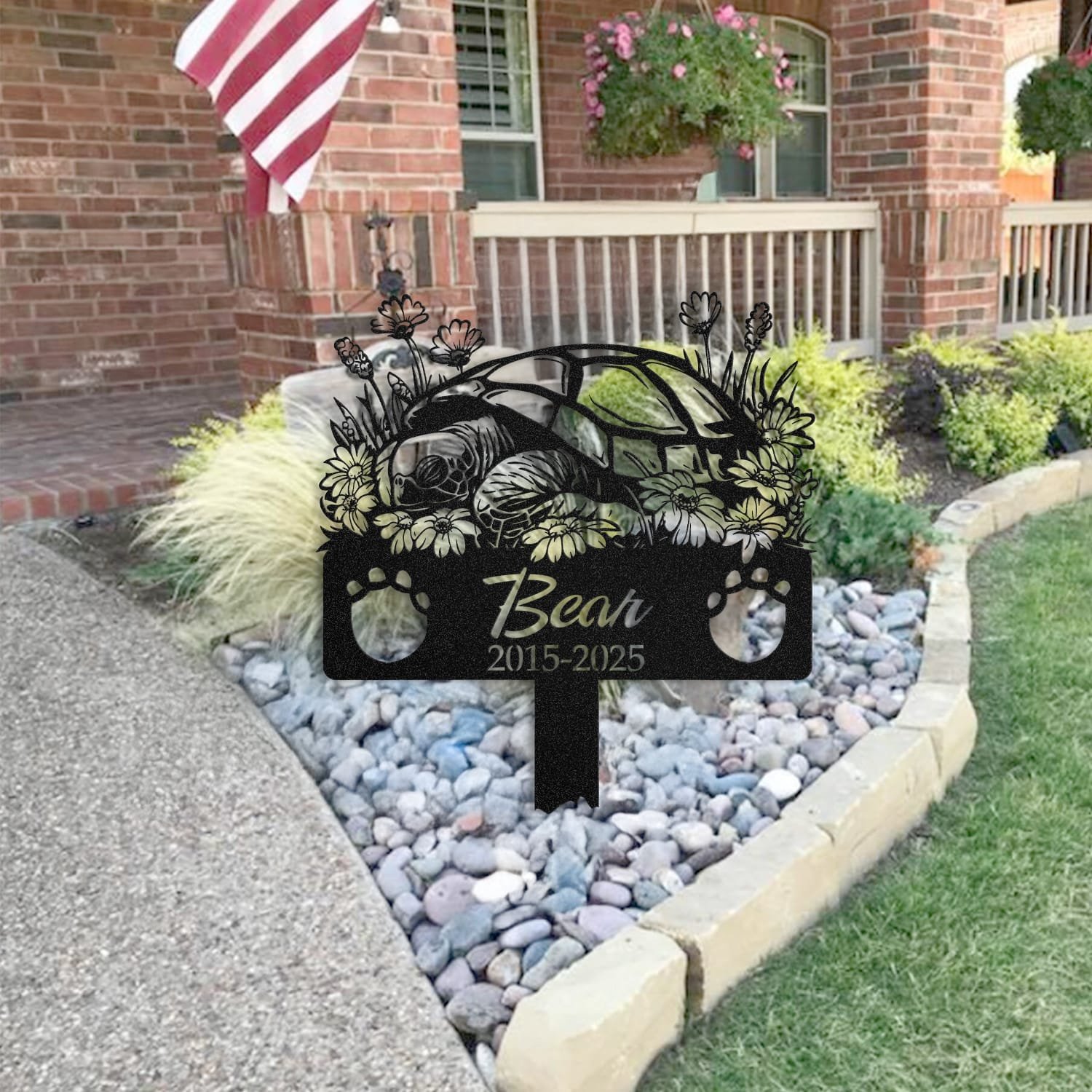 Turtle pet grave marker staged near a home entryway, showing the finished sleeping-pose daisy floral design and name plate outdoors.