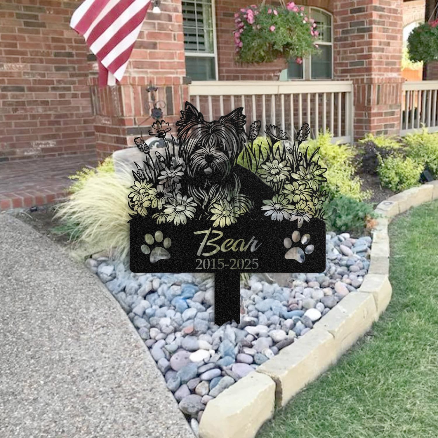 Yorkshire Terrier pet grave marker staged near a home entryway, showing the finished angel wings and daisy floral design and name plate outdoors.