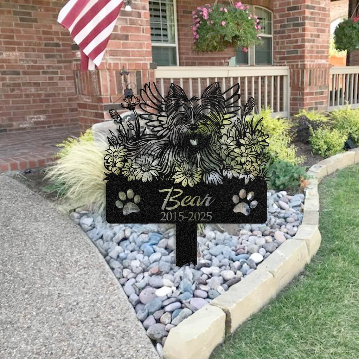 Yorkshire Terrier pet grave marker staged near a home entryway, showing the finished angel wings and daisy floral design and name plate outdoors.